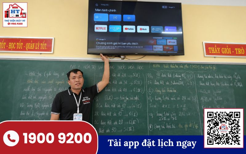 Kiểm tra tivi tại trường học Kỹ thuật viên đang kiểm tra tivi đặt trên bàn trong không gian lớp học