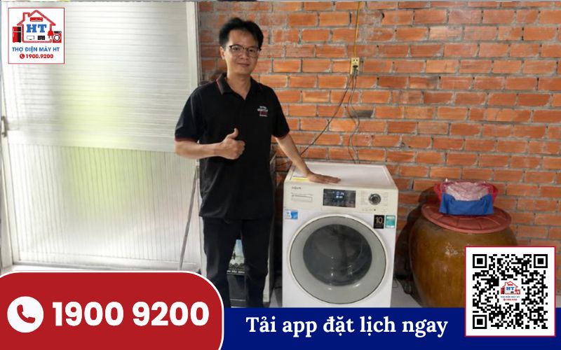 Kiểm tra máy giặt cửa trước Kỹ thuật viên đang kiểm tra máy giặt cửa trước, tập trung vào khu vực bảng điều khiển và cửa lồng giặt.