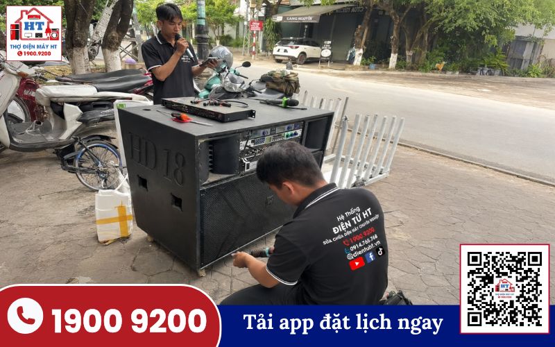 Kiểm tra mặt sau loa kéo bằng tua vít Bàn tay đang cầm tua vít mở ốc mặt sau của một chiếc loa kéo màu đen để kiểm tra bên trong.