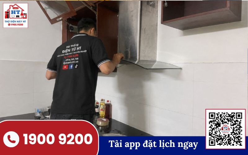 Kiểm tra máy hút mùi gắn tường Thợ kiểm tra máy hút mùi gắn tường. Người thợ đang mở nắp lưới lọc, chuẩn bị tháo hoặc lắp bộ lọc than hoạt tính.
